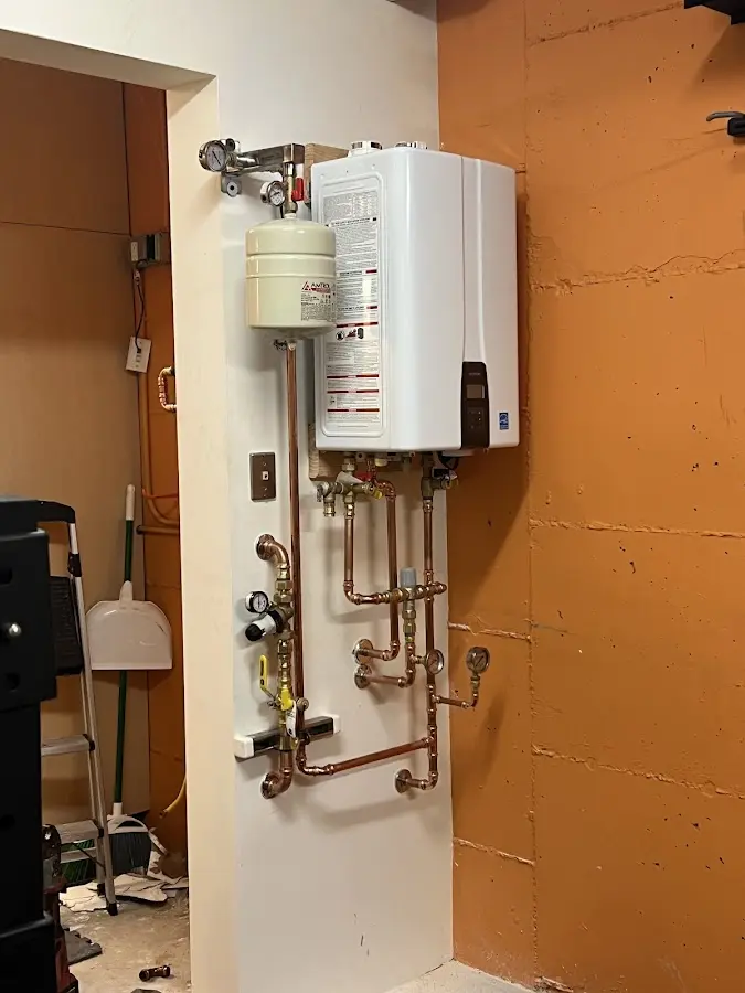 Plumbing technician inspecting water heater connections in Wellsville